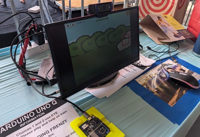 The eye-tracking station at Bay Area Maker Faire 2026: Bunny Feeding Frenzy on screen, webcam on top, Arduino UNO Q in a yellow printed case